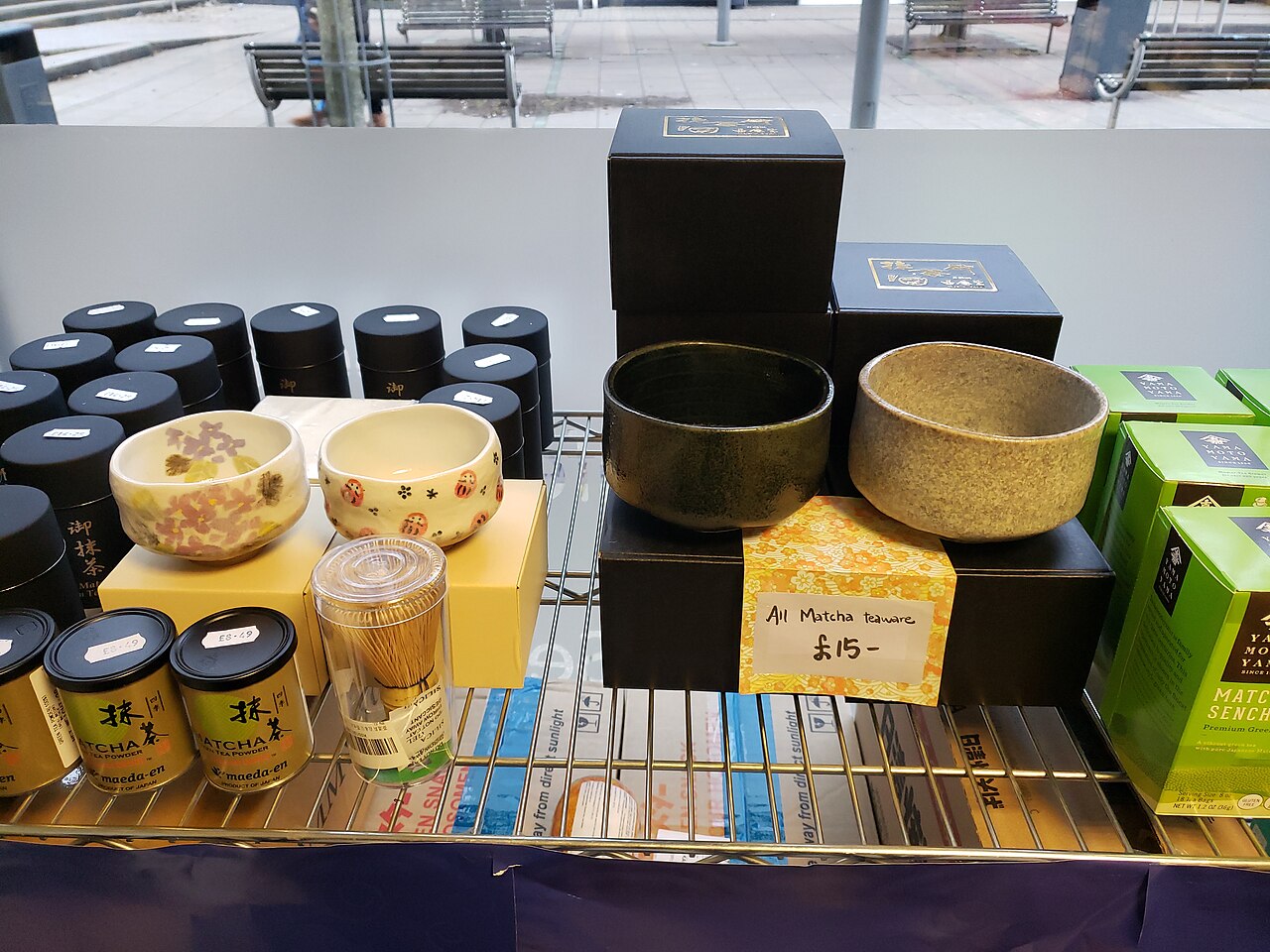 Boîtes de poudre de matcha, bols et fouet chasen en vitrine pour comparer les grades